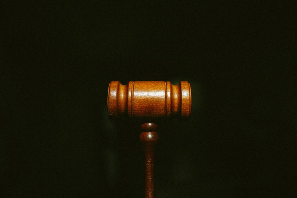 Wooden judge’s gavel resting on a block in a courtroom.